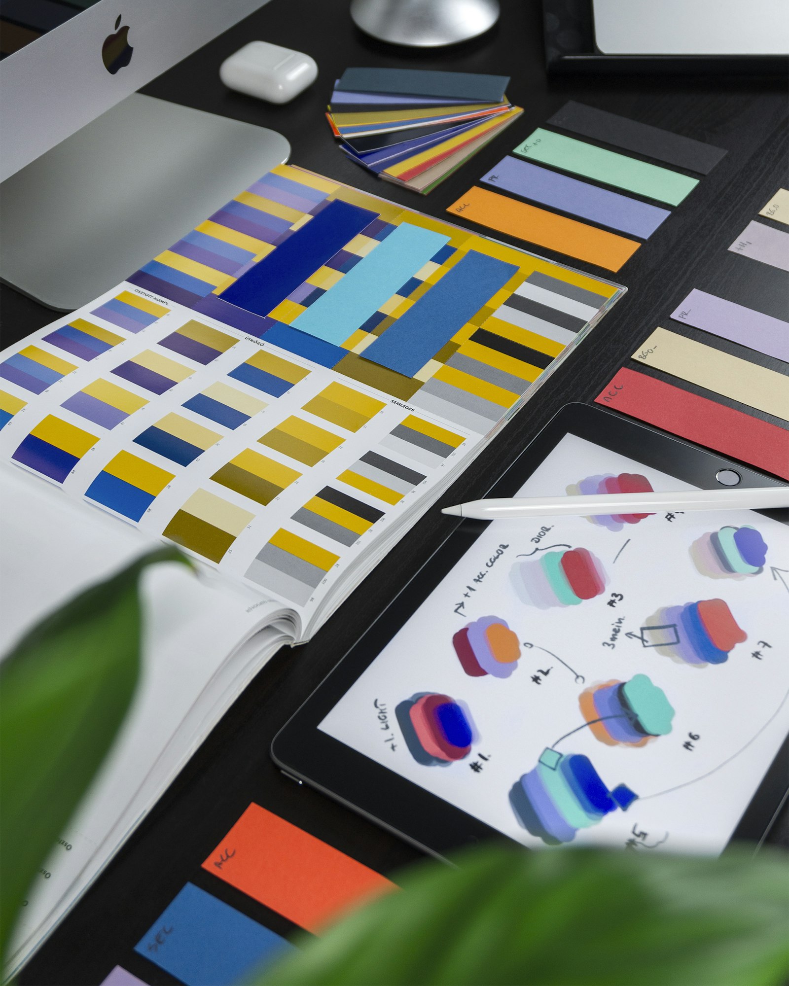 A designer's color swatch book and reference cards spread across a desk, representing a deliberately chosen color palette